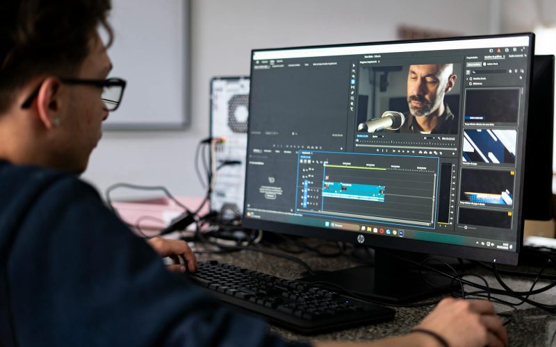 A video editor working on a project using a desktop computer in a modern office setting.